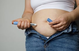 Tirzepatida y obesidad. Mujer se aplica medicamento para bajar de peso.