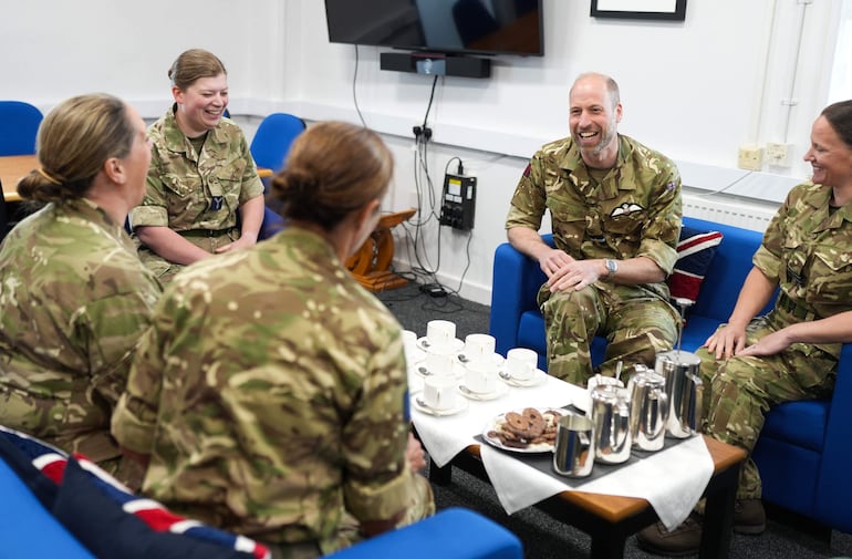 El príncipe Wiiliam conversando con miembros del equipo femenino de la RAF, lo que refleja su continuo interés en la experiencia y el bienestar de las mujeres en las Fuerzas Armadas, durante su visita a la base de la RAF en Valley, Anglesey, al noroeste de Gales. (Dominic Lipinski / POOL / AFP)