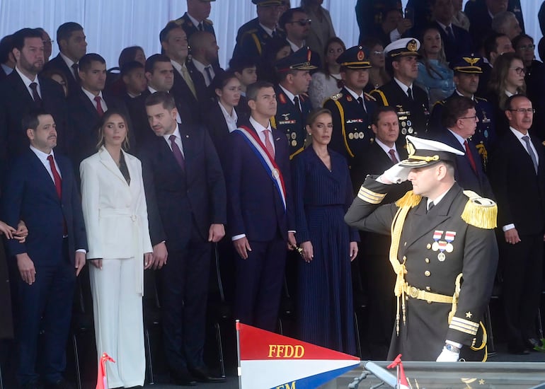 Alberto Jiménez Rolón en uniforme militar, rodeado de políticos y funcionarios en trajes formales, en un evento solemne al aire libre.