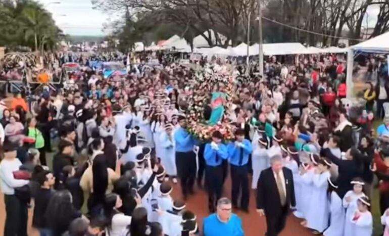 Grupo de personas en Minga Guazú, algunos en trajes tradicionales, aplaudiendo durante la procesión floral de María Auxiliadora.