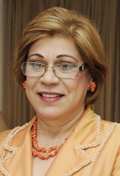 Gladys Bareiro de Módica con expresión alegre, vistiendo gafas y un collar, en un entorno formal.