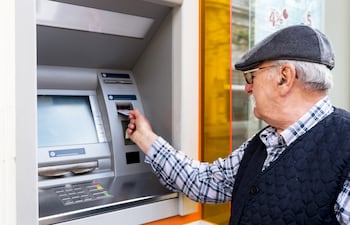 Un jubilado retira dinero de un cajero automático.