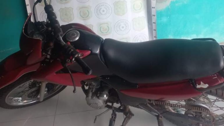 Motocicleta roja y negra en interior con fondo verde y tela de seguridad.