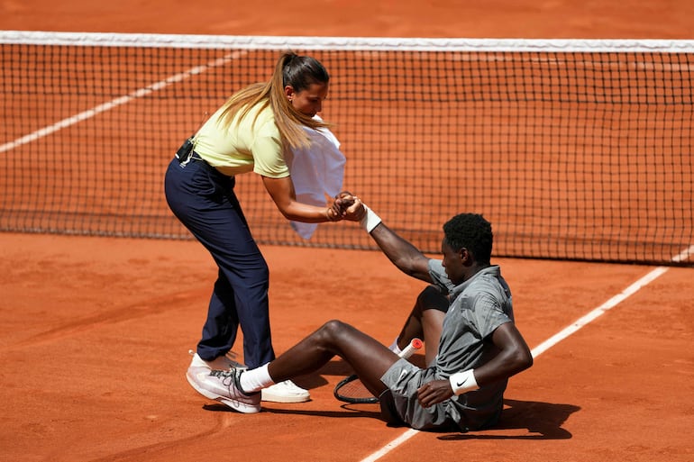 La umpire Ana Carvalho ayuda al francés Moise Kouame después de una caída durante el partido frente al paraguayo Adolfo Daniel Vallejo por la segunda ronda del Roland Garros.
