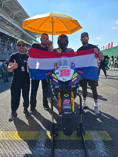 Fabrizio Almirón (izquierda), Pedro Valiente (centro), Hassen David (derecha) e integrantes del equipo Superbike Paraguay, llevando la bandera tricolor bien en alto.