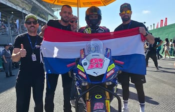 Fabrizio Almirón (izquierda), Pedro Valiente (centro), Hassen David (derecha) e integrantes del equipo Superbike Paraguay, llevando la bandera tricolor bien en alto.