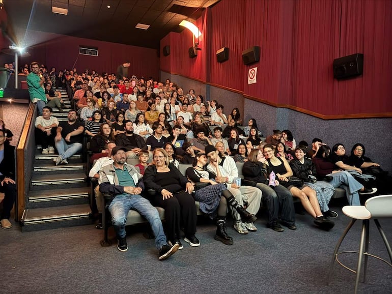 Sala del Casino Oberá llena de personas de diversas edades, esperando la película 'Gente de la Ruta' con un presentador de pie.
