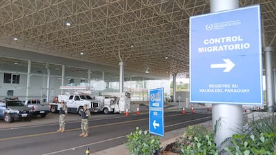 Soldados uniformados en control migratorio, atentos y vigilantes, rodeados de vehículos en un área estructurada.