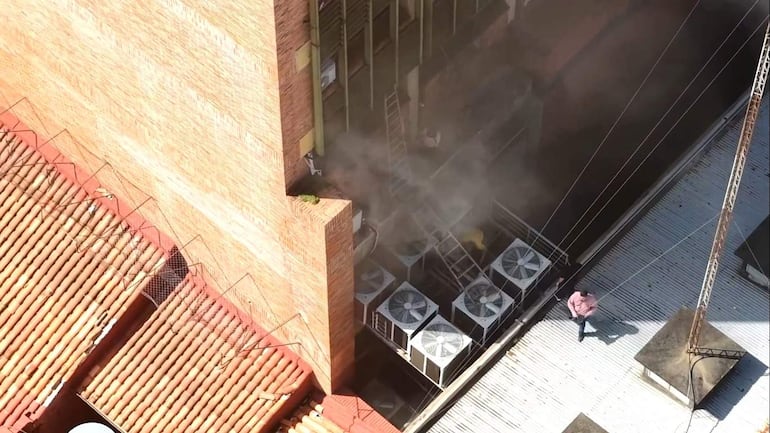 Vista aérea del edificio de Ahorros Paraguayos con humo saliendo de unidades de aire acondicionado y cordón de seguridad.