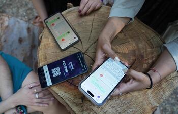 Miembros de la Red de Defensoras Digitales del movimiento Ley Olimpia, Vania Sisai Rodríguez, Marcela Hernández y Salma Semiramis, muestran cómo funciona la plataforma OlimpIA en su teléfono durante una entrevista con la AFP en Ciudad de México.