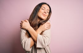 Una mujer se abraza a sí misma.