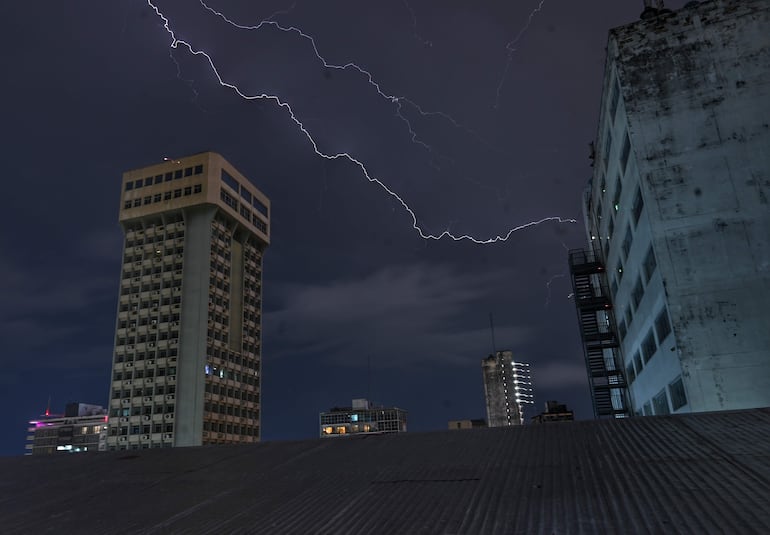 Paisaje urbano nocturno con rayo en el cielo, edificios modernos y un ambiente solitario.