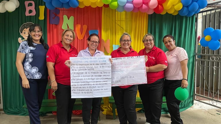 Profesoras con carteles en protesta por cambios planteados en la caja fiscal.