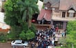 Multitud de más de 100 personas frente a casa, algunas con abrigos, ambiente de expectativa y atención hacia un orador.