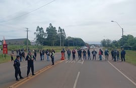 Grupo de personas en protesta en la carretera, con policías controlando el acceso, en un día nublado.