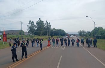 Grupo de personas en protesta en la carretera, con policías controlando el acceso, en un día nublado.