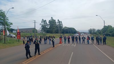 Grupo de personas en protesta en la carretera, con policías controlando el acceso, en un día nublado.
