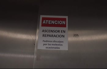 Cartel rojo y blanco en metal que indica el ascensor en reparación en el IPS, sin personas visibles.