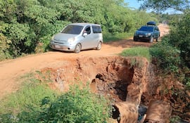 Un automovilista cruza arriesgándose el enorme alcantarillado desmoronado.