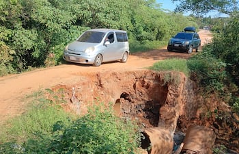 Un automovilista cruza arriesgándose el enorme alcantarillado desmoronado.