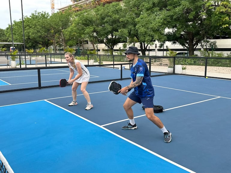 El pickleball se practica en una cancha más pequeña que la de tenis, con paletas sólidas y una pelota plástica perforada.