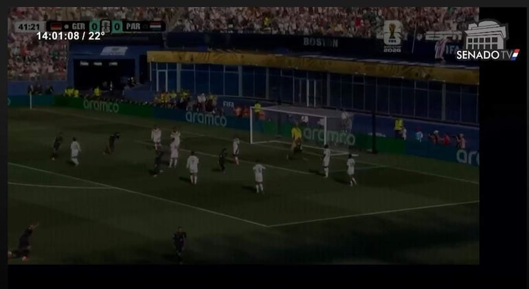Jugadores en acción en un partido de fútbol, con un futbolista de Paraguay con balón mientras el público observa entusiasta.