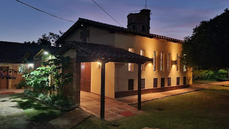 Construcción de la Capilla San José iluminada al anochecer, rodeada de un jardín bien cuidado.