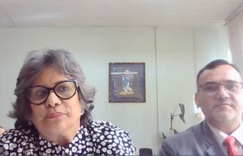 Laura Ocampo con cabello rizado y gafas habla, mientras Fabián Weisensee la escucha atentamente, en un entorno formal.