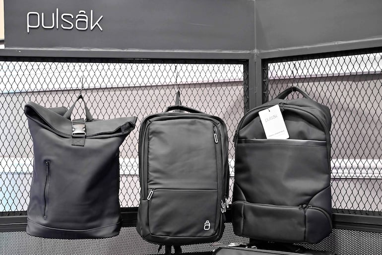 Tres mochilas negras de la marca pulsák en exhibición, dispuestas sobre estructura metálica en un ambiente comercial bien iluminado.