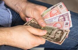 Un hombre sostiene billetes de guaraníes.
