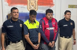 El agente de PMT Nicolas Fariña, vestido de uniforme, junto a Diego Isabelino Vera en camiseta de Cerro Porteño, tras ser detenidos por incidentes en el Superclásico.