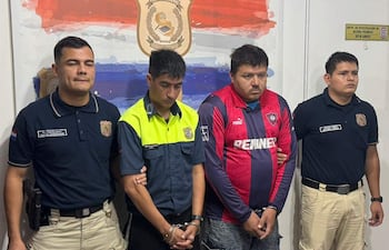 El agente de PMT Nicolas Fariña, vestido de uniforme, junto a Diego Isabelino Vera en camiseta de Cerro Porteño, tras ser detenidos por incidentes en el Superclásico.