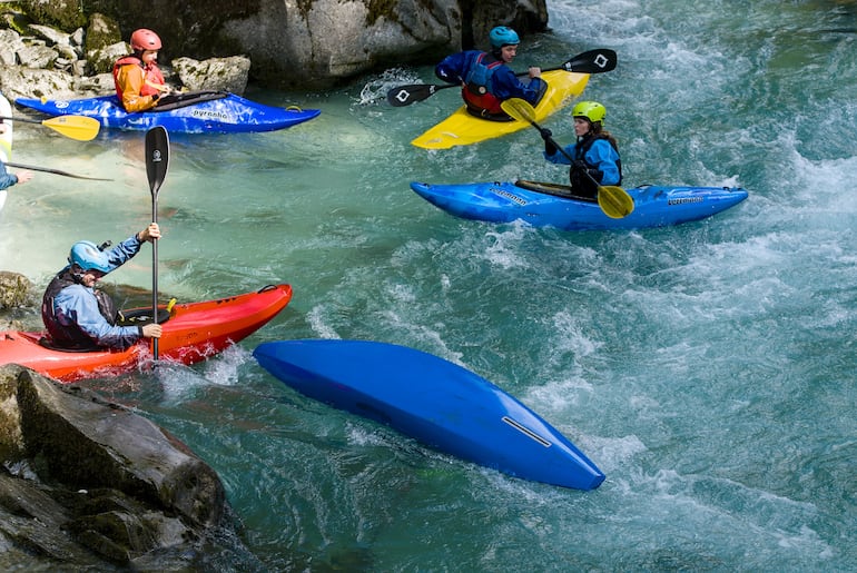 El instructor de Kayak observa cuidadosamente cómo el estudiante saldrá de la situación con el kayak derrocado en Bovec, Eslovenia.
