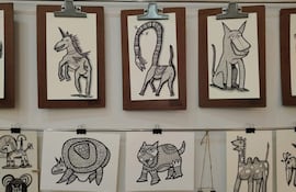 Varias ilustraciones de animales como un unicornio y una tortuga, enmarcadas, expuestas en paneles sobre soporte marrón.