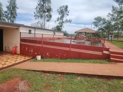 Escena vacía de un resort con piscina cercada y gazebo, sin personas visibles y cielo parcialmente nublado.
