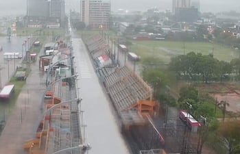 Vista aérea de calles inundadas en Encarnación, con camiones y edificios de fondo bajo cielo nublado.