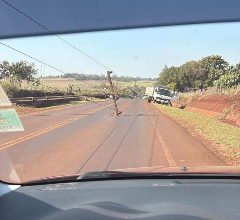 Poste de luz caído sobre la carretera, con un camión detenido en el lado, en un ambiente rural seco.