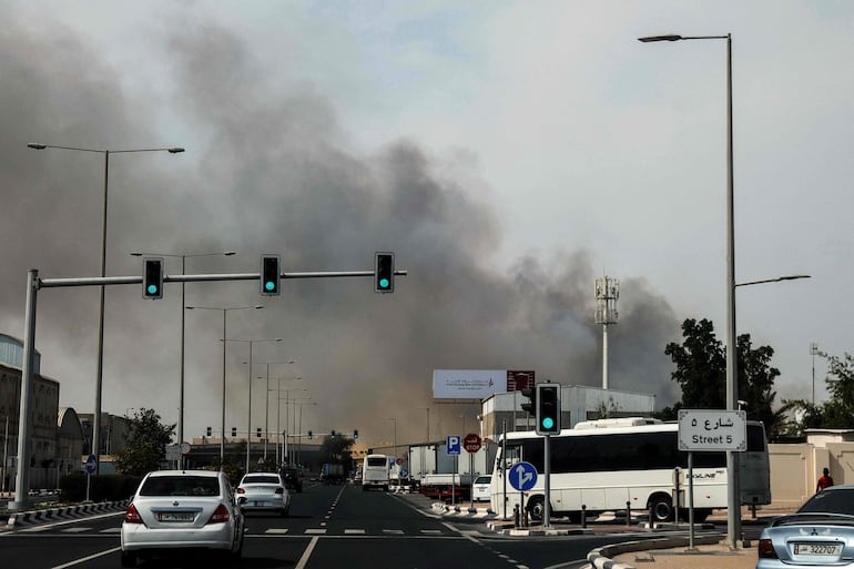 Automovilistas pasan junto a una columna de humo que se elevaba tras un supuesto ataque iraní en el distrito industrial de Doha el 1 de marzo de 2026.