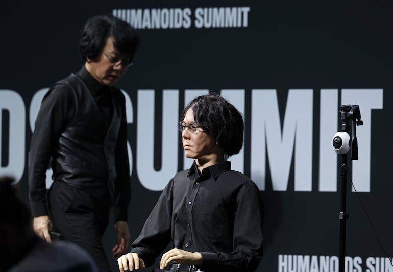 El robotista e ingeniero japonés Hiroshi Ishiguro pasa junto a su copia androide durante la Humanoids Summit en Tokio, Japón, el 28 de mayo de 2026.