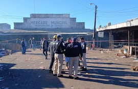 Horacio Fernández y varios propietarios en el Mercado Municipal de Itauguá, con entorno desordenado y humo visible.
