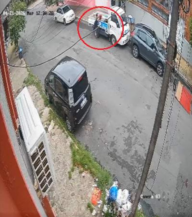 Una persona junto a un vehículo blanco en una calle con tráfico, sin rostros visibles ni emociones destacadas.