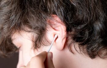 Un joven se limpia la oreja con un cotonete