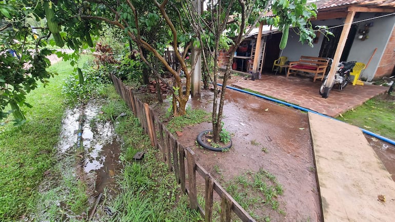 Vivienda de familia con canal de desagüe afectado y vegetación alrededor, sin personas visibles en la imagen.