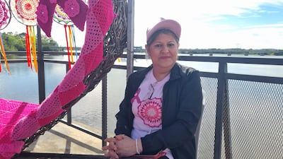 Lucía Ayala sentada en un muelle, con gorra rosa y camiseta blanca, mirando a la cámara en un día soleado.