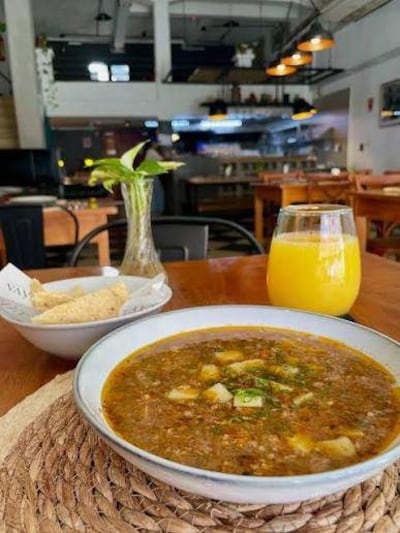 Ambiente acogedor en restaurante con un guiso tradicional y vaso de jugo de naranja sobre la mesa.