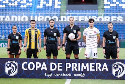 El árbitro central David Elías Ojeda (con el balón en la mano), los capitanes Lucas Quintana y Luis Martínez Soto, y los demás componentes del staff referil en campo, antes del partido entre Guaraní y Cerro Porteño, finalizado 1-1.