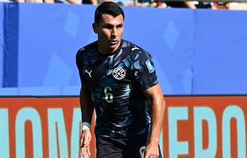 Junior Alonso, con camiseta azul oscuro y número 6, se prepara para patear el balón en un estadio lleno de espectadores.