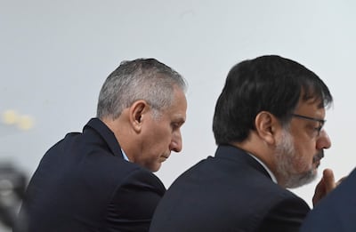 Claudio Lovera y Óscar Boidanich sentados en la sala, ambos en traje oscuro, con expresiones reflexivas.