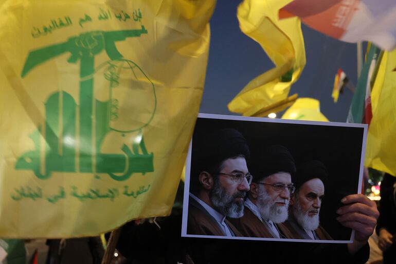 Seguidores del grupo proiraní libanés Hezbolá sostienen una imagen con los  rostros de los ayatolás iraníes, el actual líder supremo  Mojtaba Jamenei; Alí  Jamenei (falleció en febrero bajo ataque israelí) y el ayatolá y fundador de la República Islámica, Ruhollah Jomeini. 