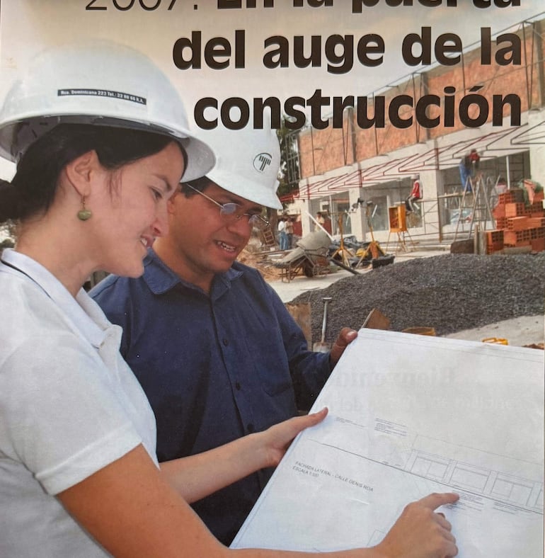 Soledad Núñez sonríe con casco blanco y camisa clara, mientras sostiene un plano junto a Juan Alberto Migliore en un entorno de obra.